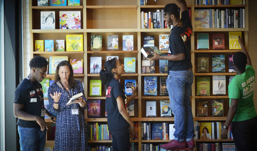 A woman reaching a hand up to a shelf